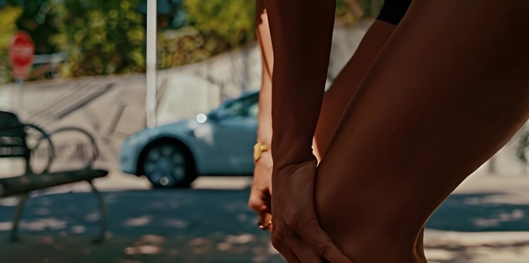 Person stretching leg outdoors near car